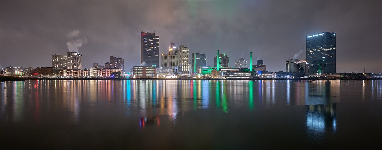 Downtown Toledo, Ohio skyline lit up at night, reflected in the Maumee River